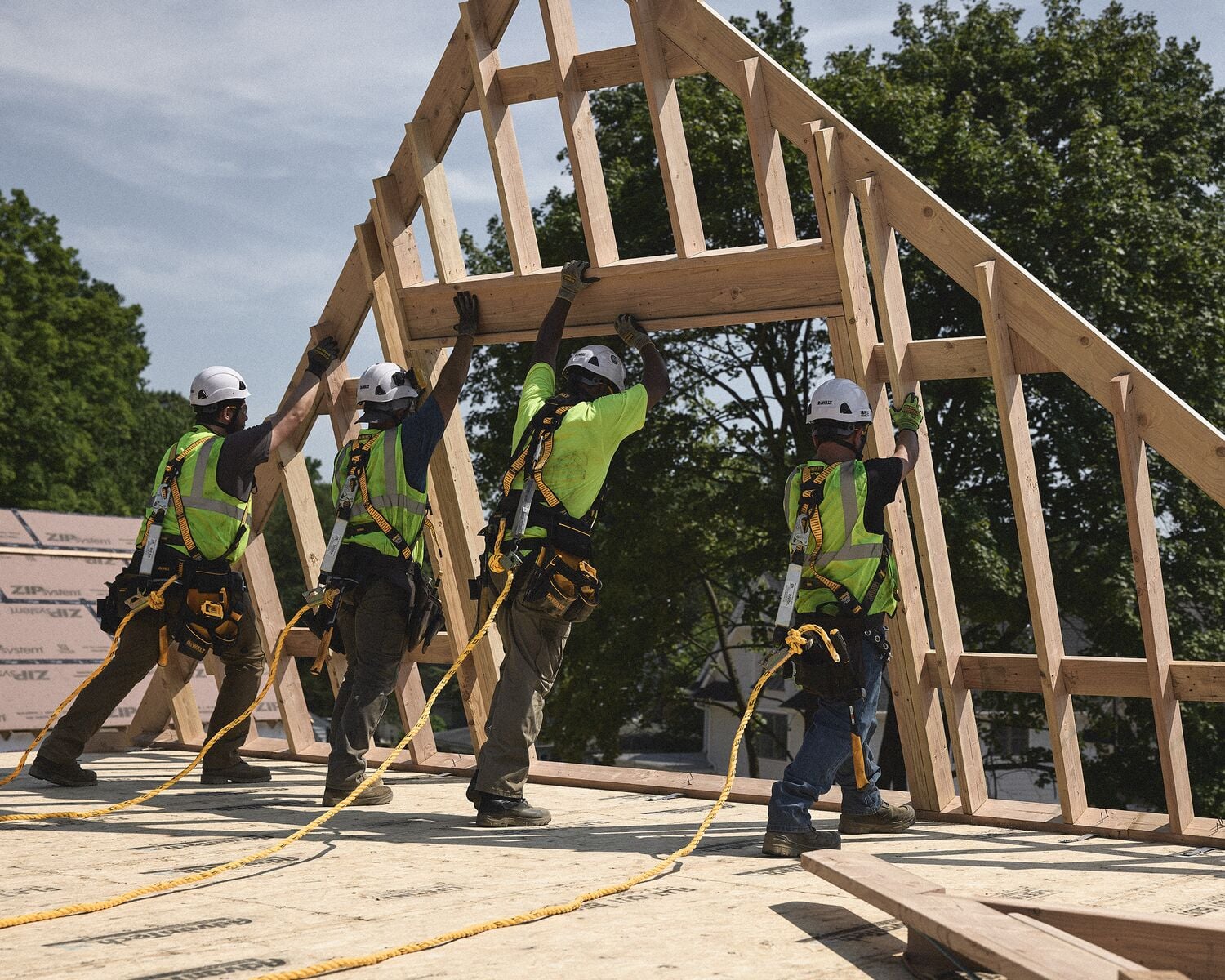 Four tradespeople hoist up a frame