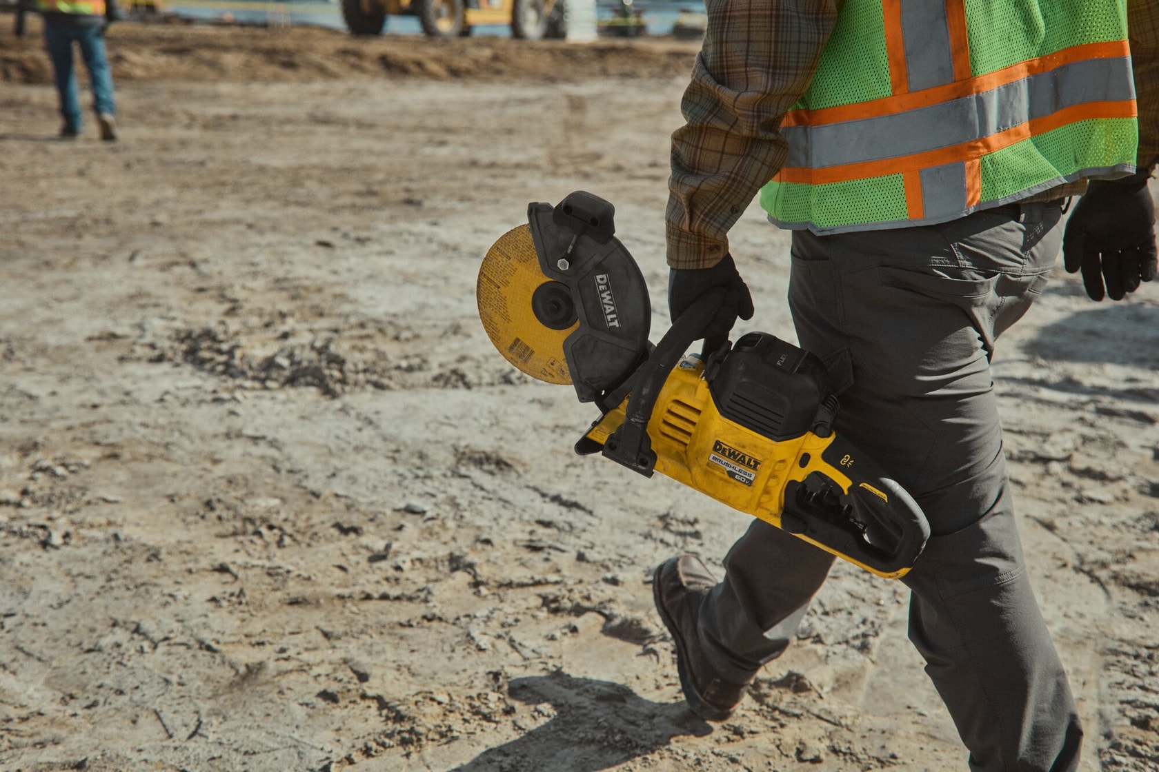 Concrete worker carrying DEWALT 60V MAX* cut-off saw