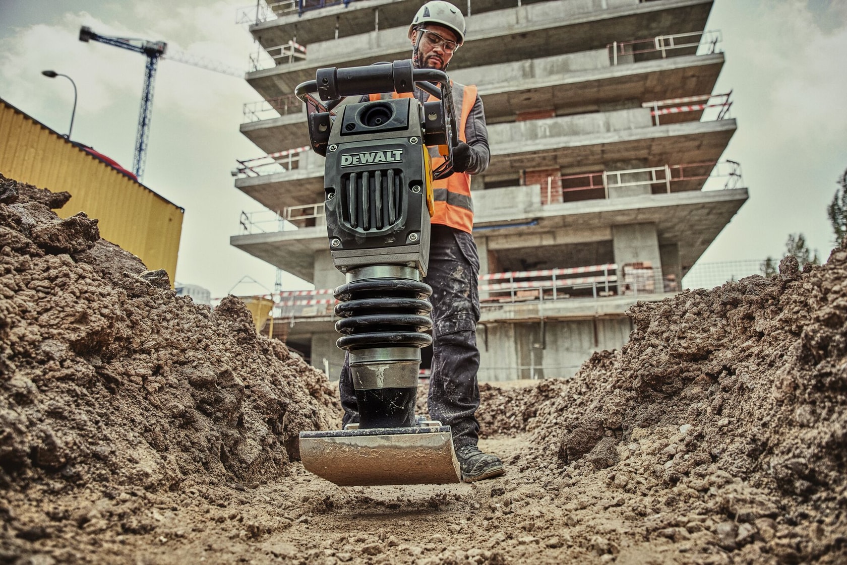 Man operating rammer in dirt trench